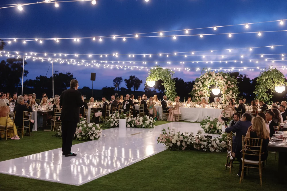 Market-light canopy glowing over a twilight wedding toast at The Lodge at Torrey Pines