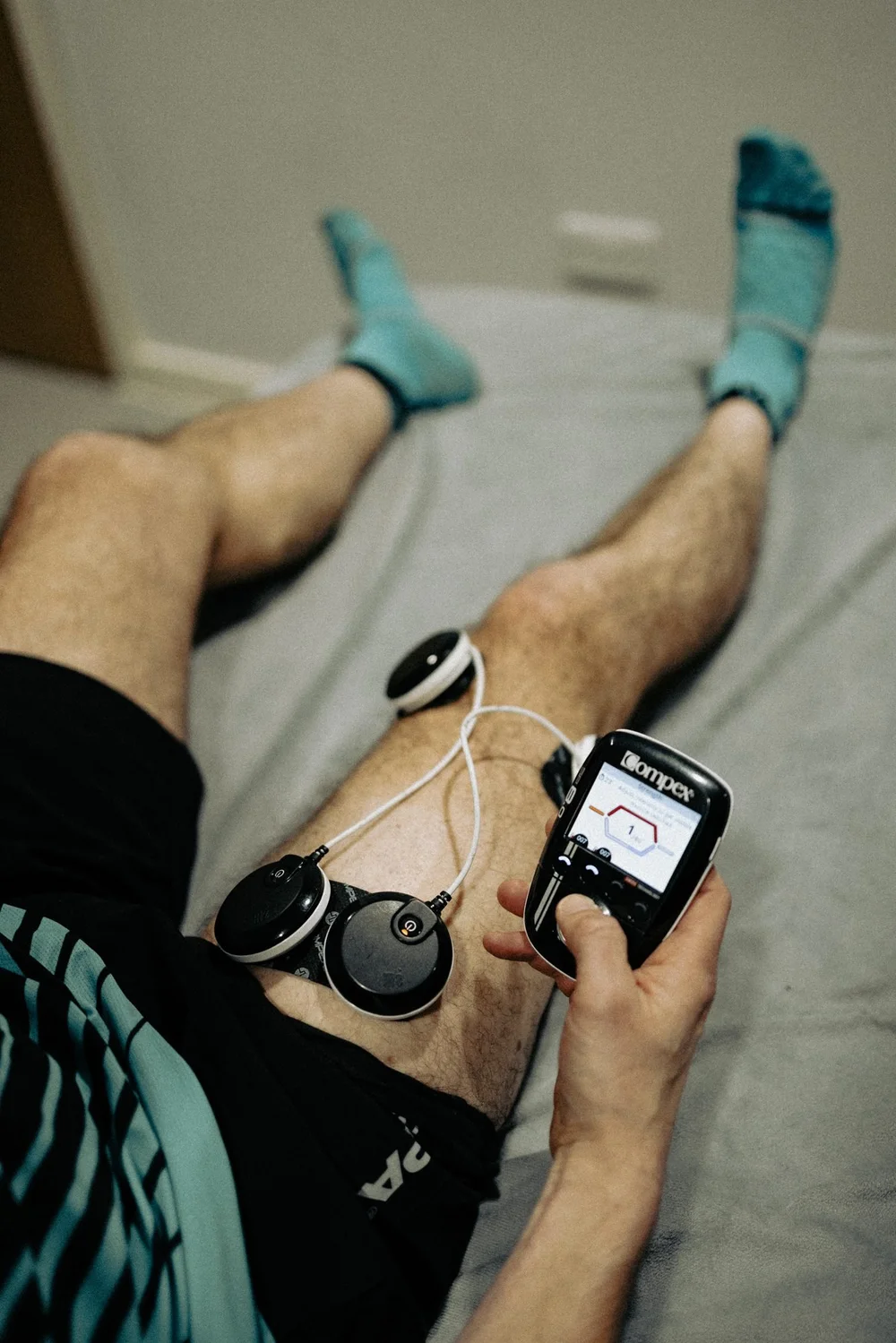 An athlete lying on a treatment bed checking heart rate data on a watch, with a sensor attached to the chest