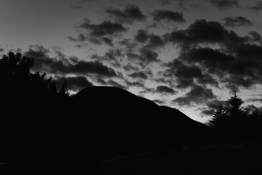 Clouds breaking over a dark hillside at first light
