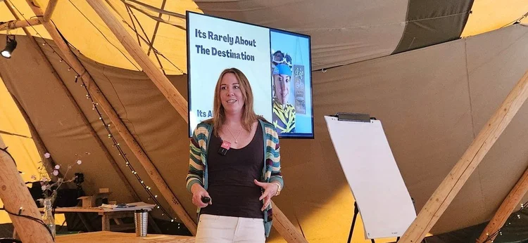 Clare Walkeden facilitating a workshop inside a tipi, standing beside a flip chart and screen