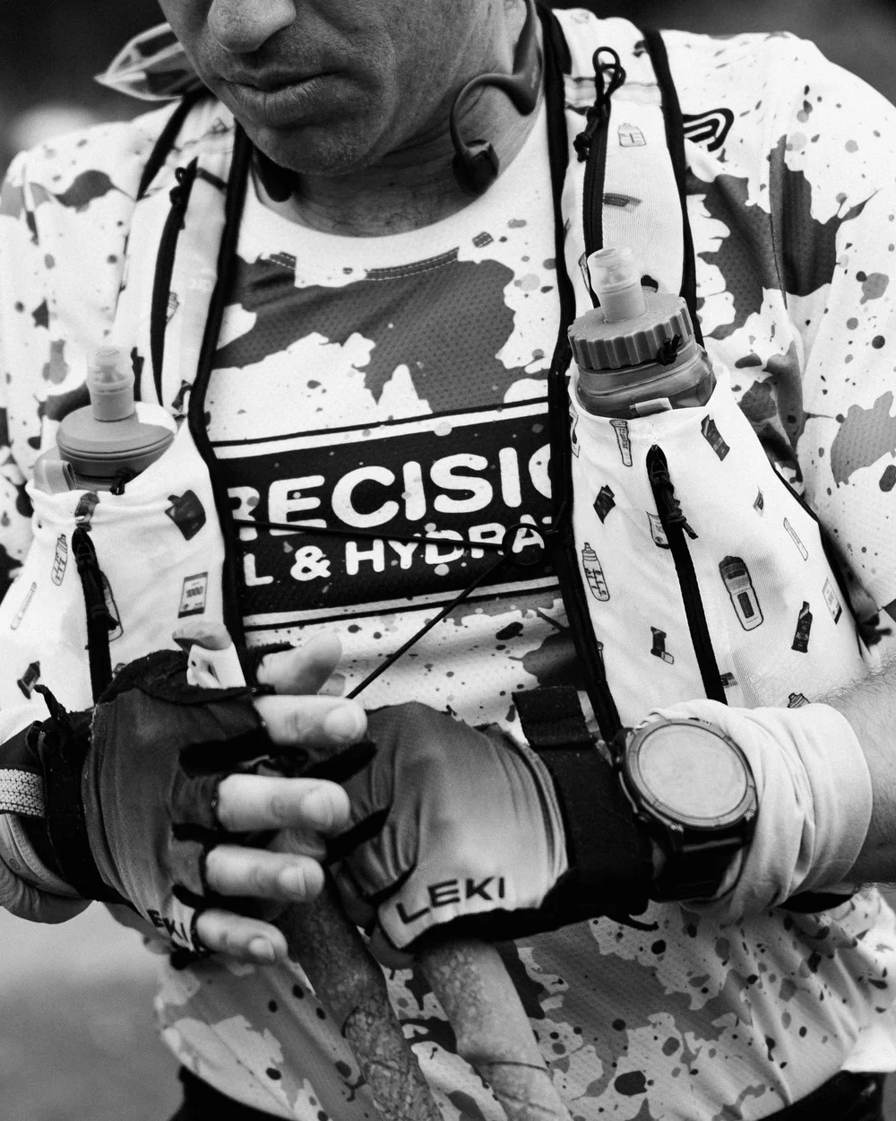 Two soft flasks in the chest pockets of an ultrarunner's vest, poles in hand