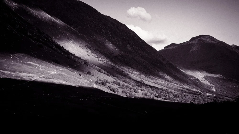 Low light across a mountain pass under a clouded sky