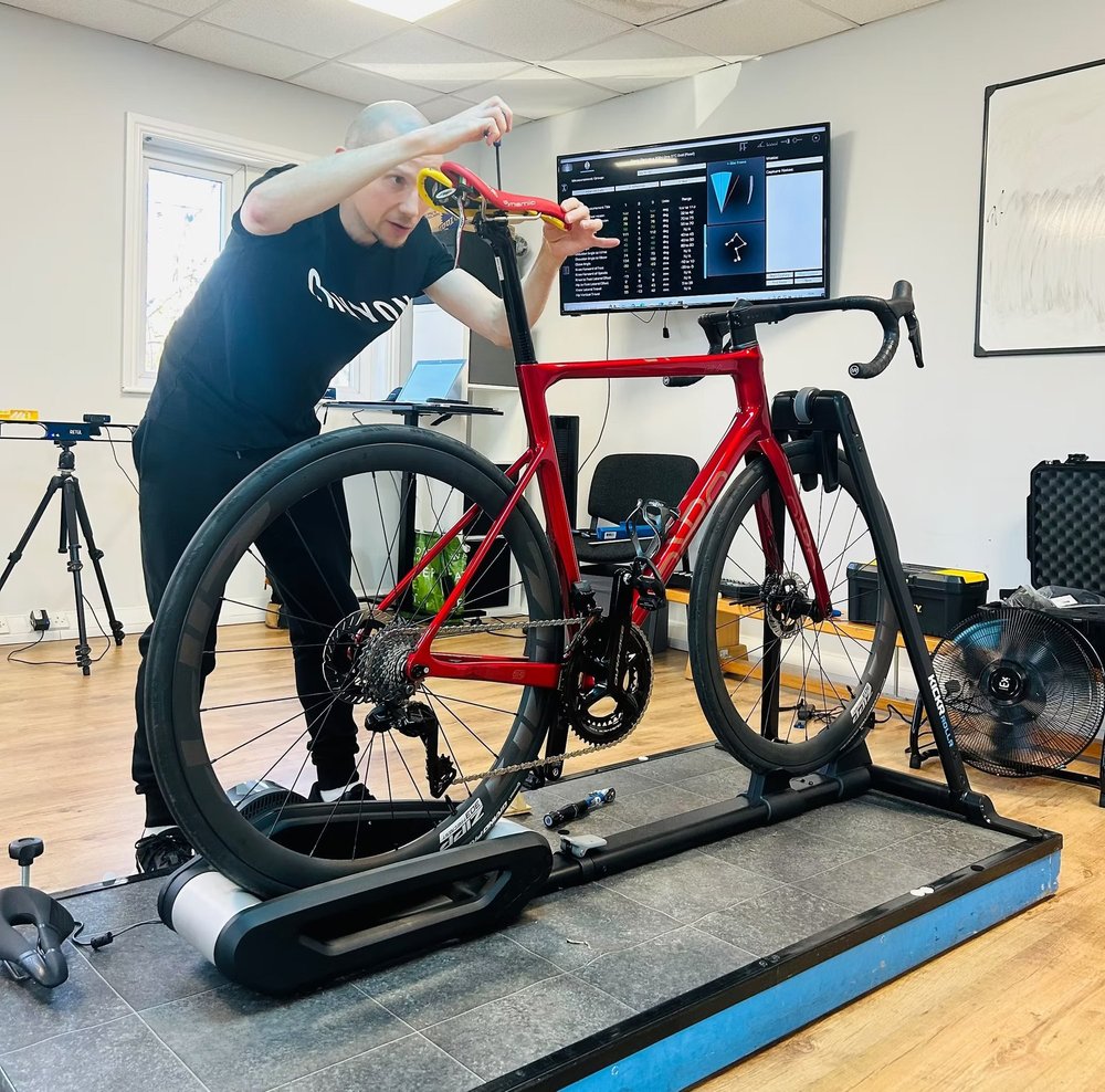 Will Beauchamp adjusting the saddle on a rider's road bike during a bike fit at Worsley Physiotherapy Clinic