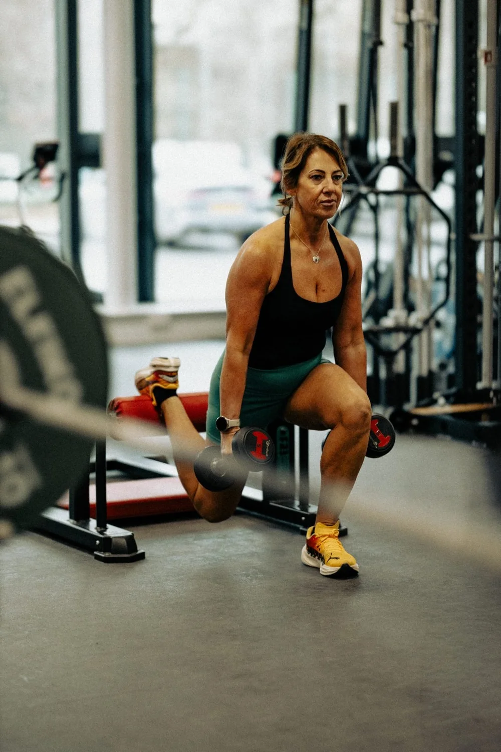 An athlete holding a loaded lunge with dumbbells, looking ahead