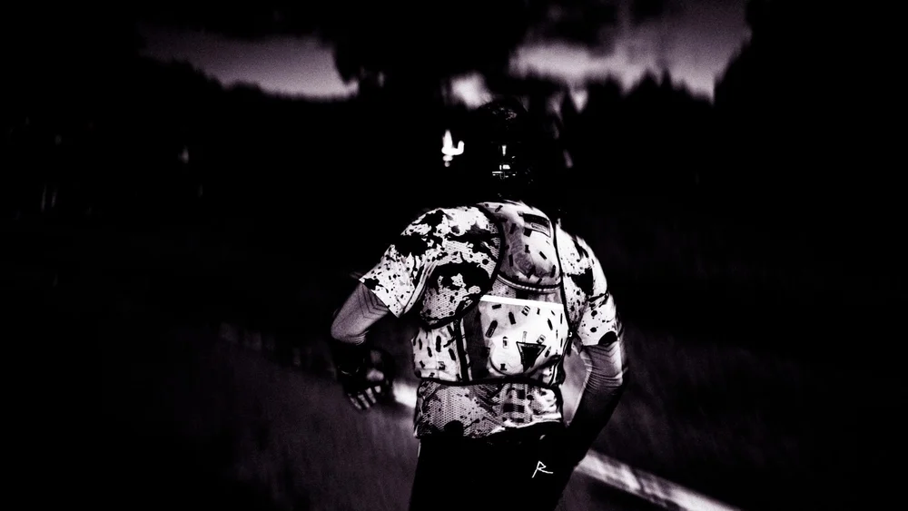 A runner seen from behind at dusk with a head torch on