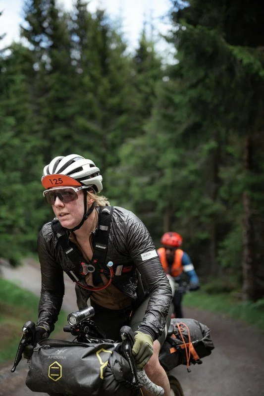 Clare Walkeden riding a fully loaded gravel bike through forest during a self-supported ultra cycling event