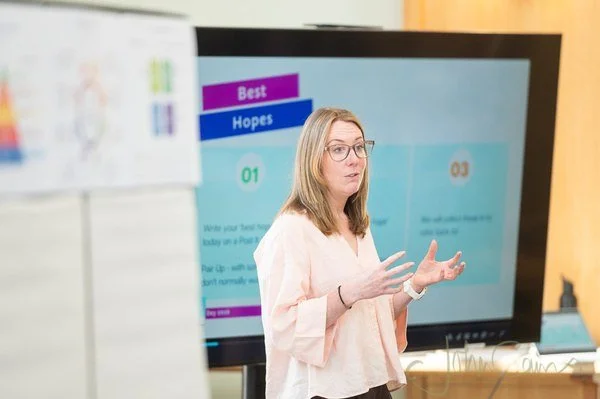 Clare Walkeden presenting to a group in front of a screen showing a goal-setting exercise