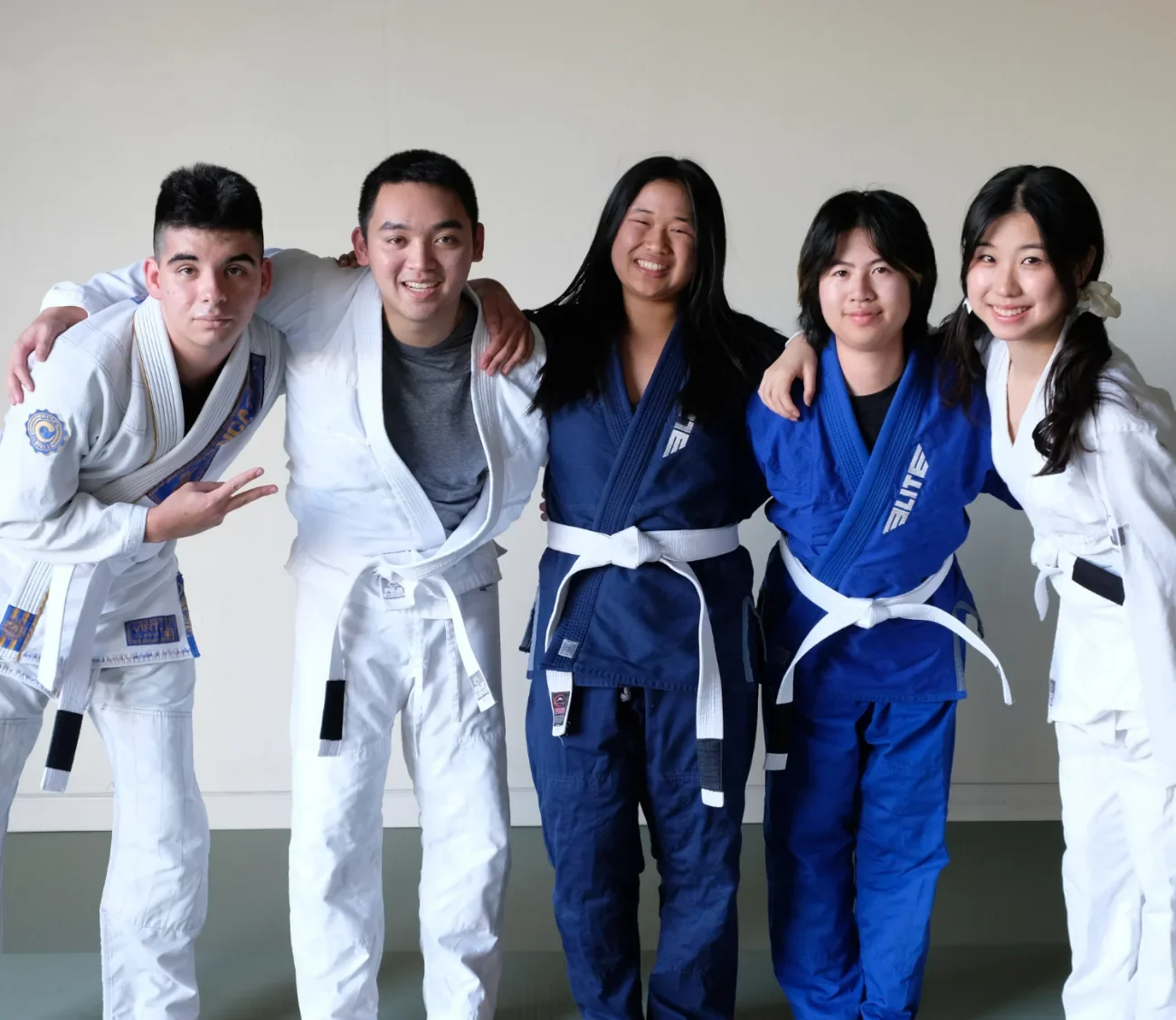 Five Budo Scholar students in their gis, arms around each other