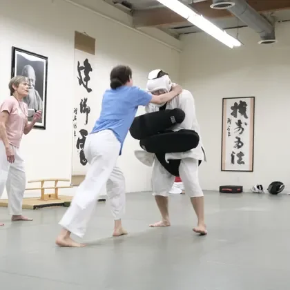 Students training on the mat while an instructor watches