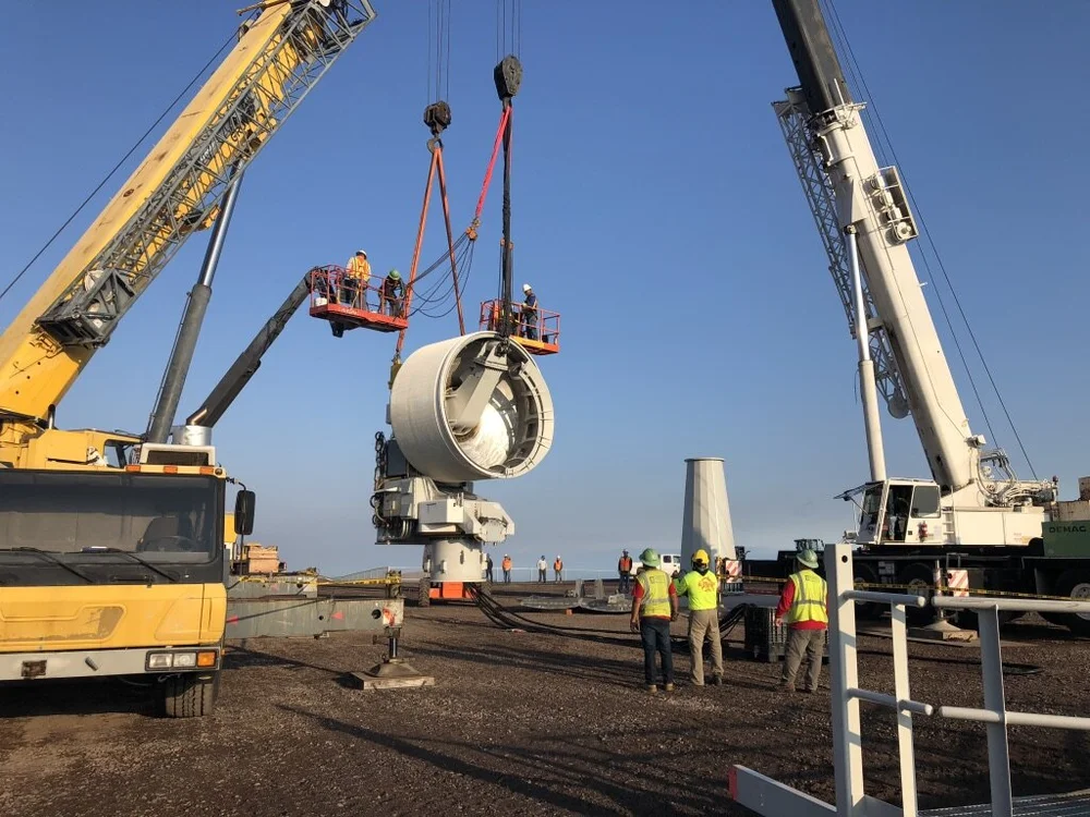 Two cranes lifting a Makani ground station into place