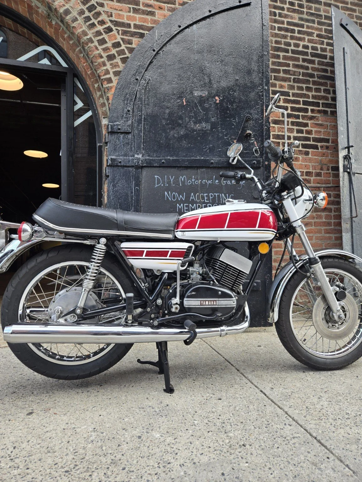 Red and white Yamaha RD350 outside the workshop