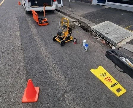 CCTV drain camera reel and pipe locator set up at a kerbside stormwater pit with safety cones
