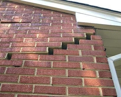 Stepped crack in a brick wall beside a window frame