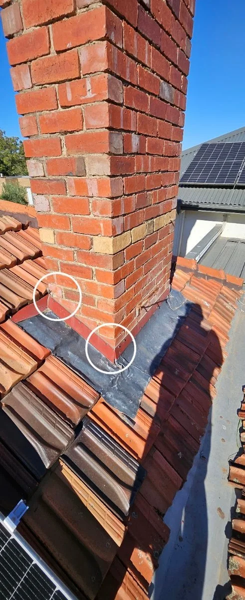 Chimney flashing on a tiled roof circled where it can let water in
