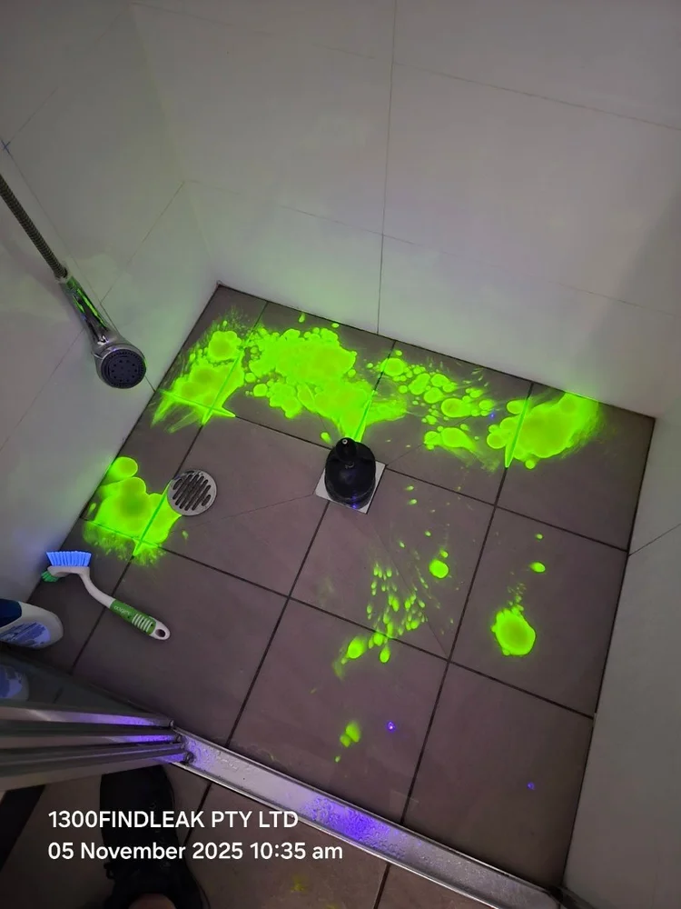 UV tracer dye glowing across a shower floor during a leak test