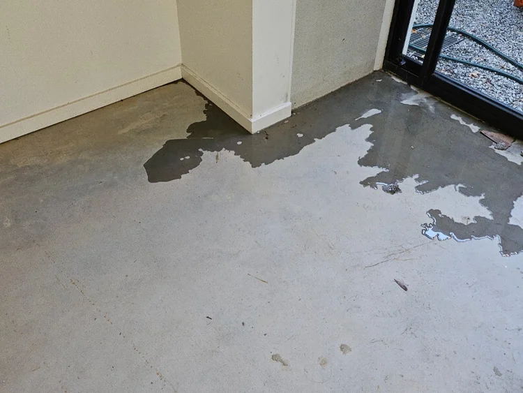 Water pooling on an apartment slab inside a sliding door after carpet removal