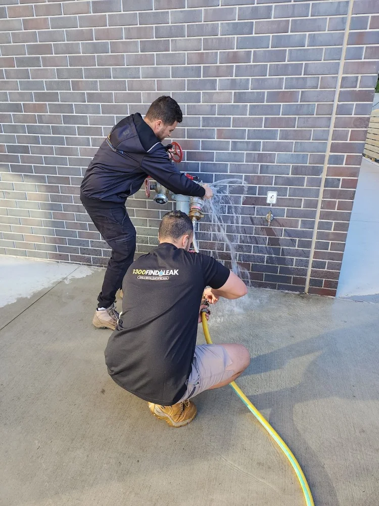 Two 1300 FINDLEAK technicians testing a fire hydrant booster on a Melbourne commercial building