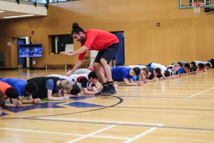 ED leaping over a line of campers during a plank drill at summer camp