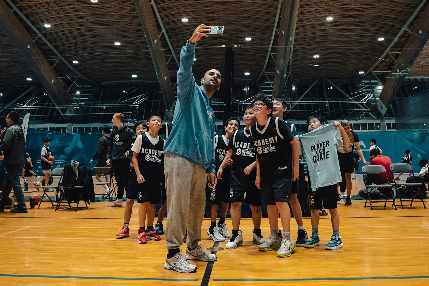 An Academy coach takes a selfie with his celebrating team, one player holding the Player of the Game shirt