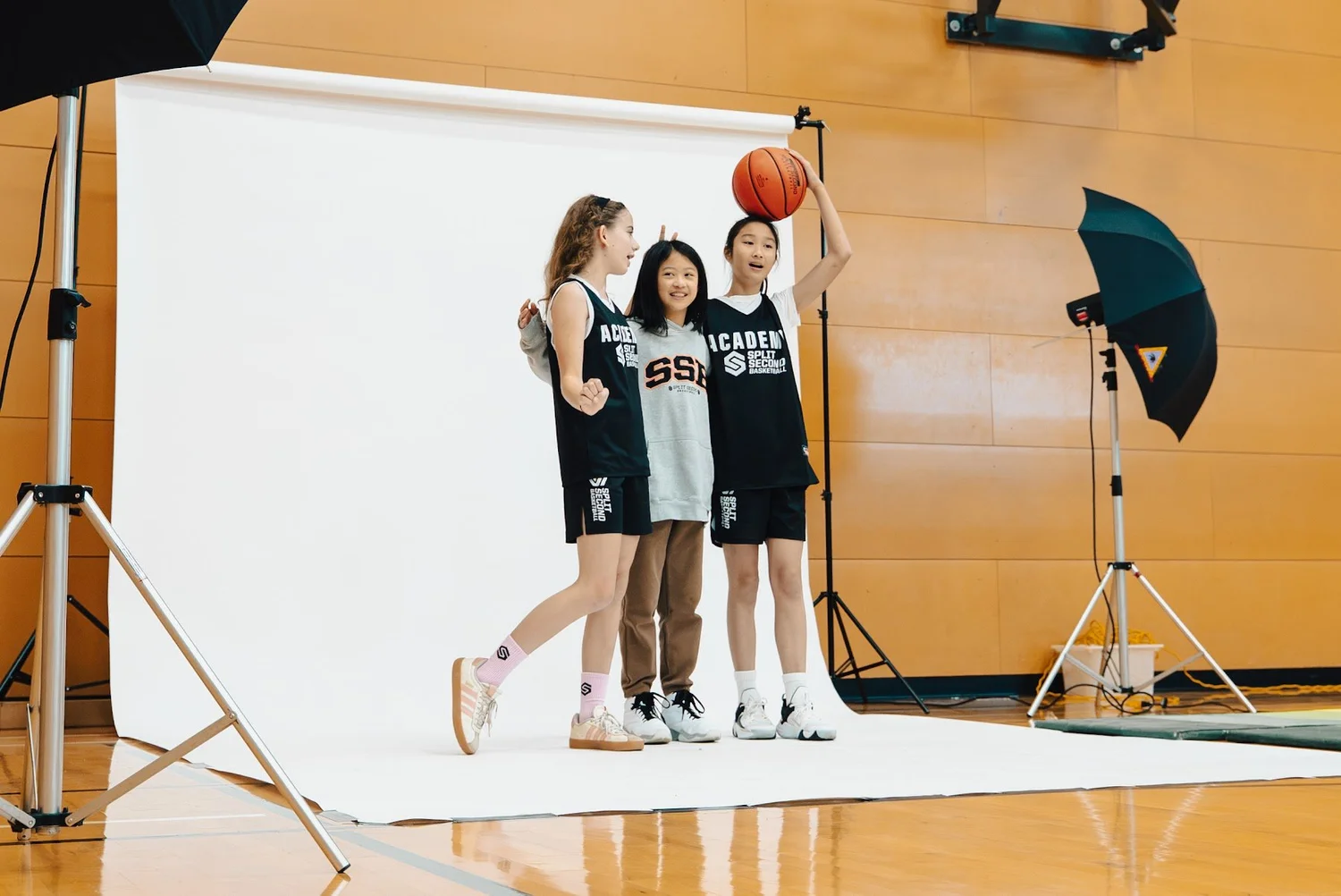 Three Academy players posing with a basketball on the studio set