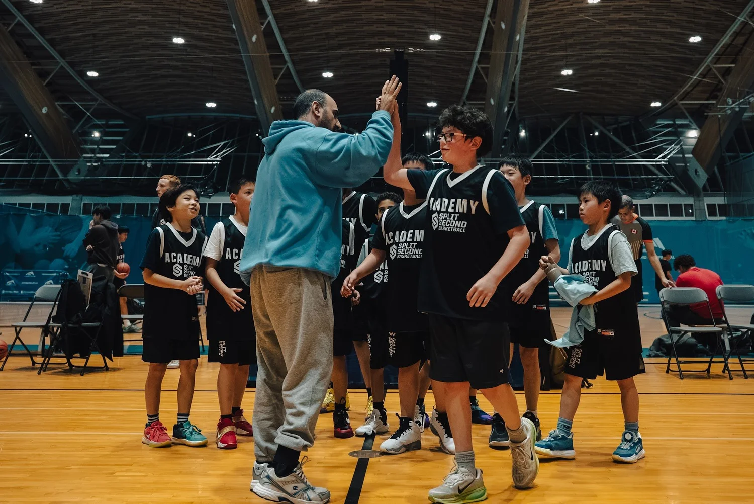 A coach and player share a high-five in front of the team