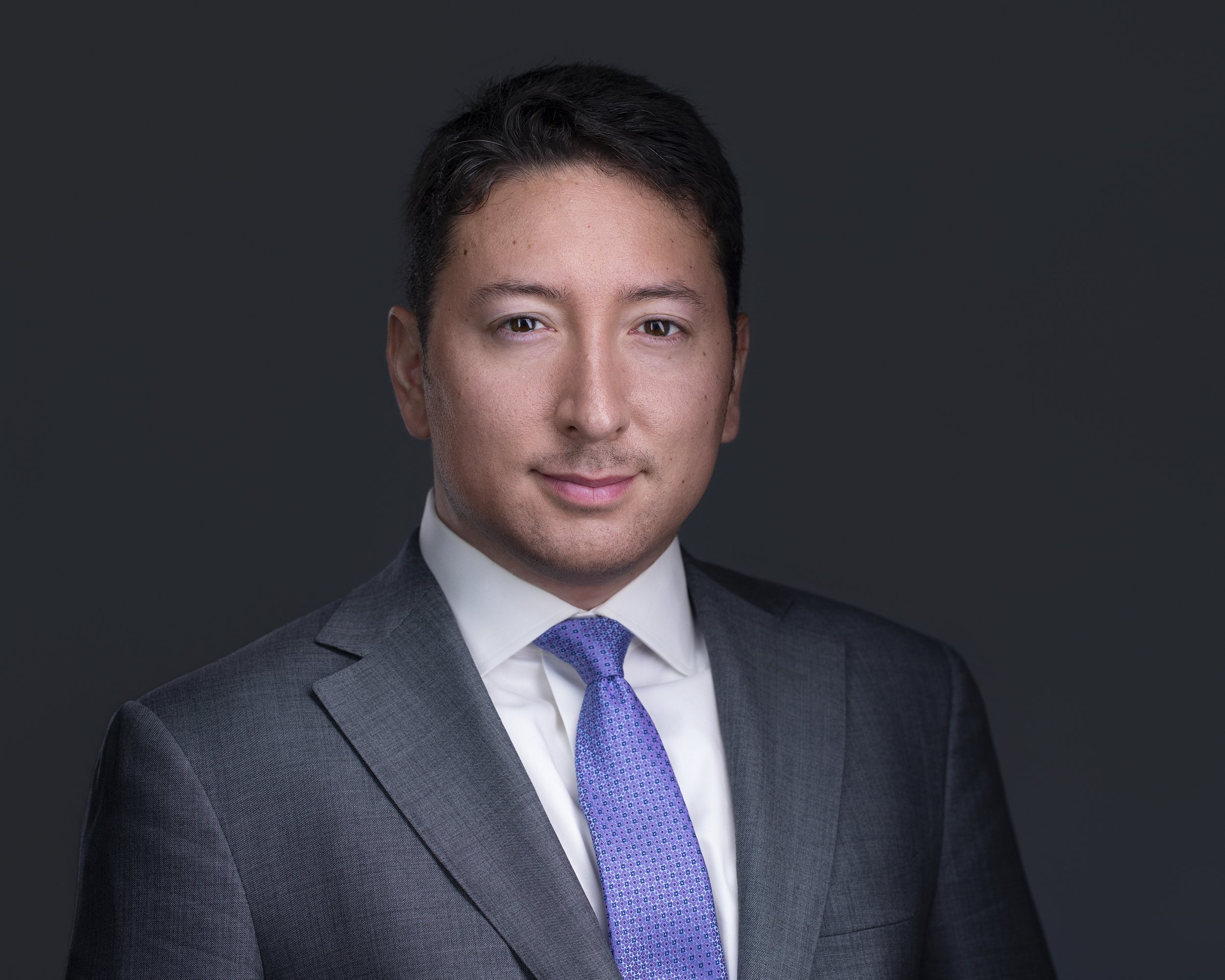 Studio headshot of Cristian wearing a gray suit