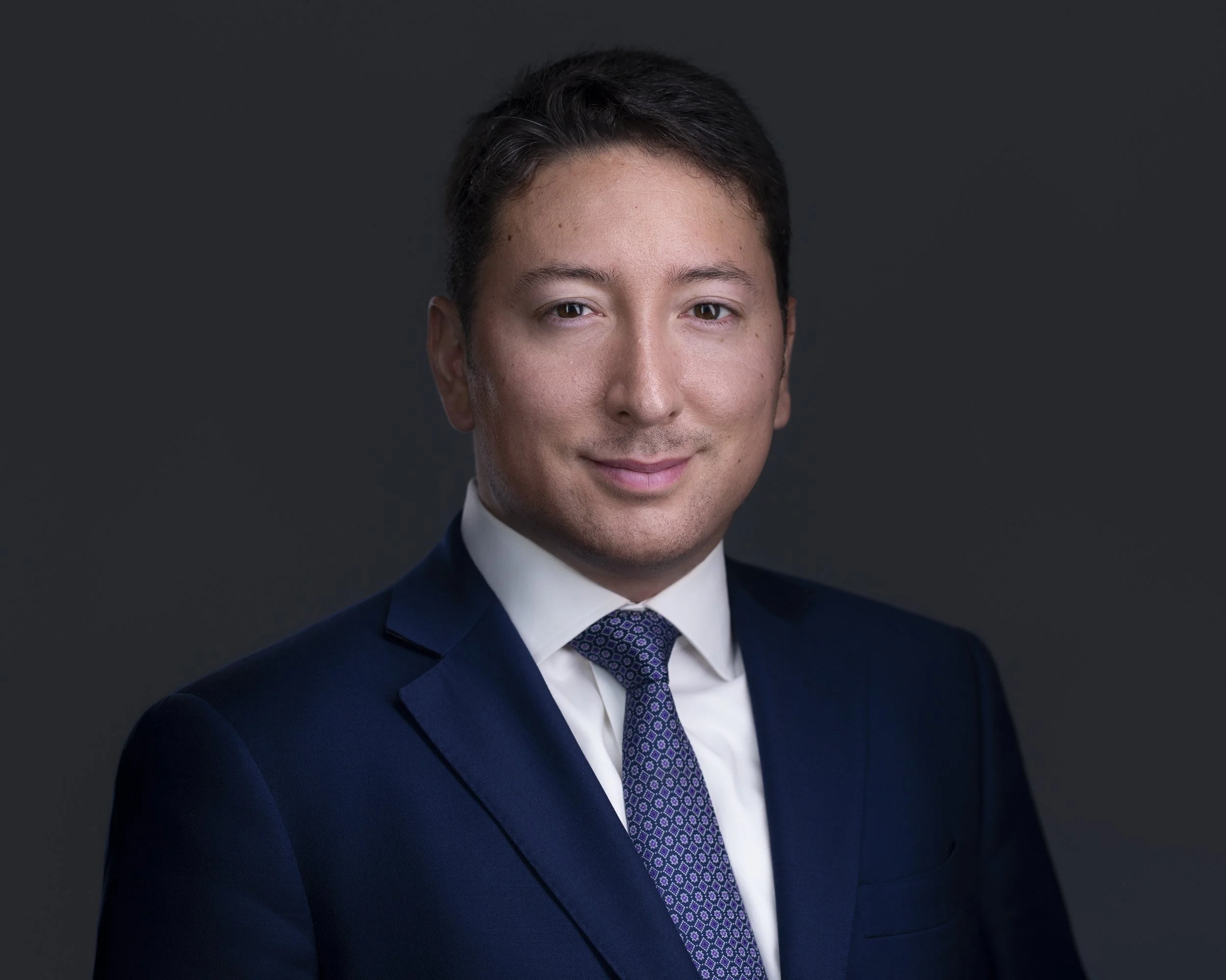Studio headshot of Cristian wearing a navy suit