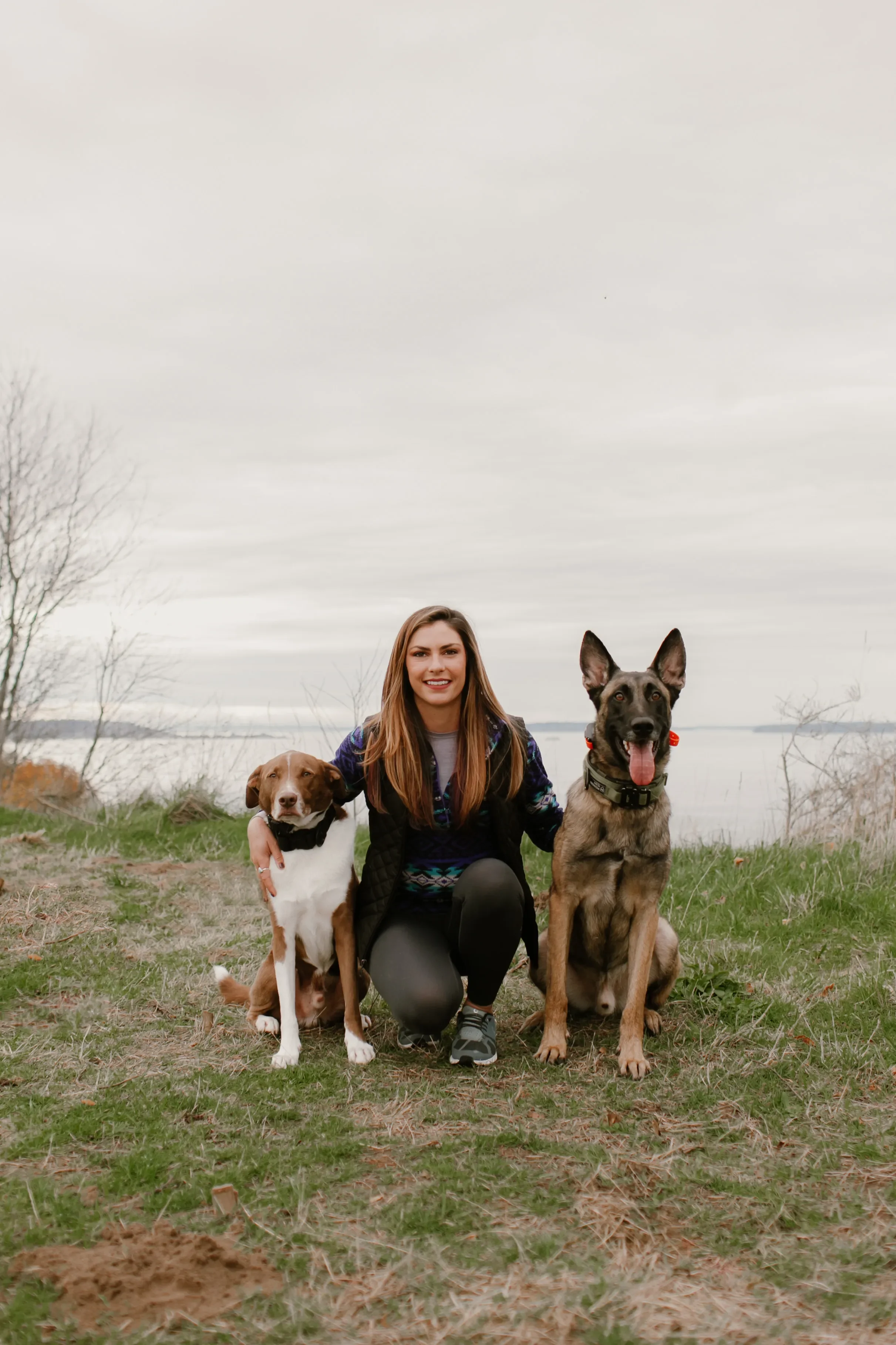 Rachel Mark, Seattle-area dog trainer, posing with two calm, attentive dogs near the Puget Sound waterfront.