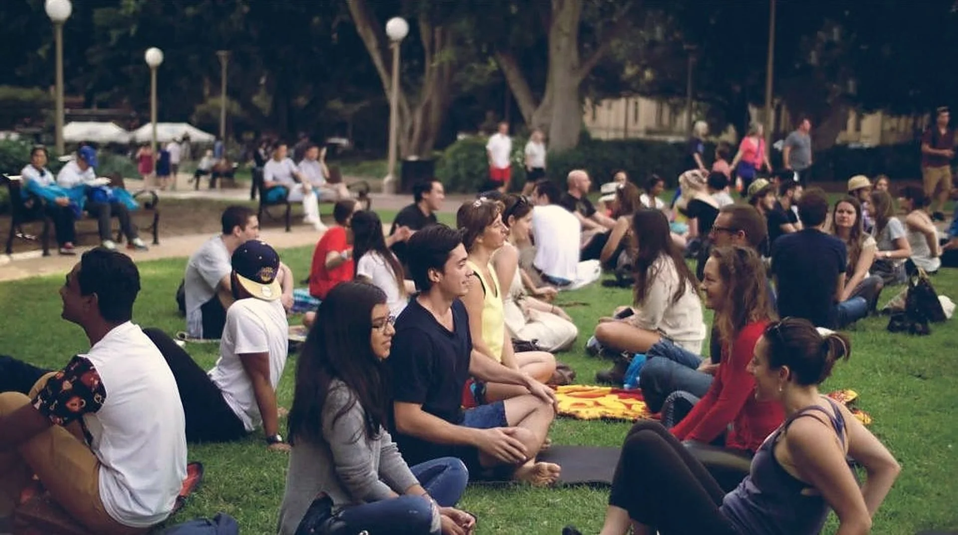 Strangers sitting in pairs on the grass in Hyde Park, Sydney