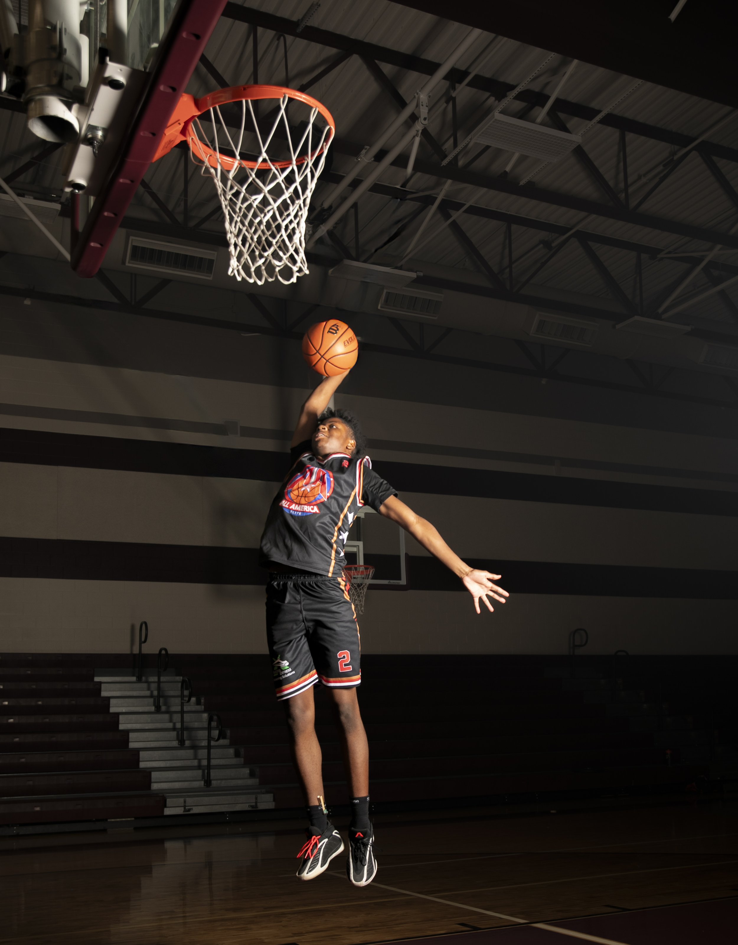 Basketball athlete jumping toward the rim in a dramatic sports portrait