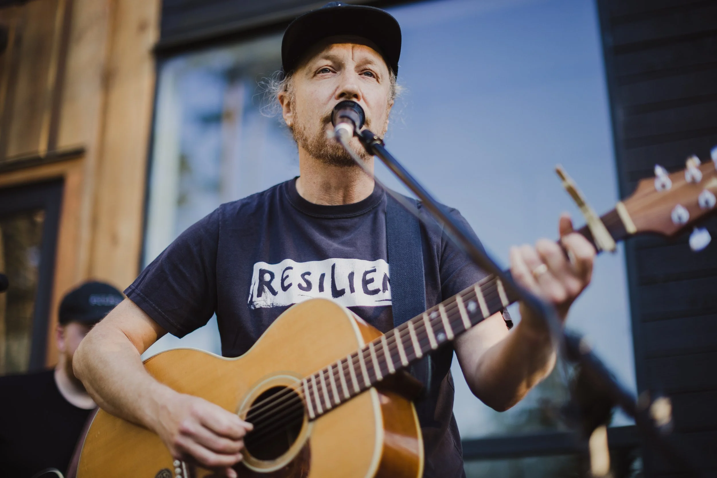 Daryl singing and playing acoustic guitar outdoors