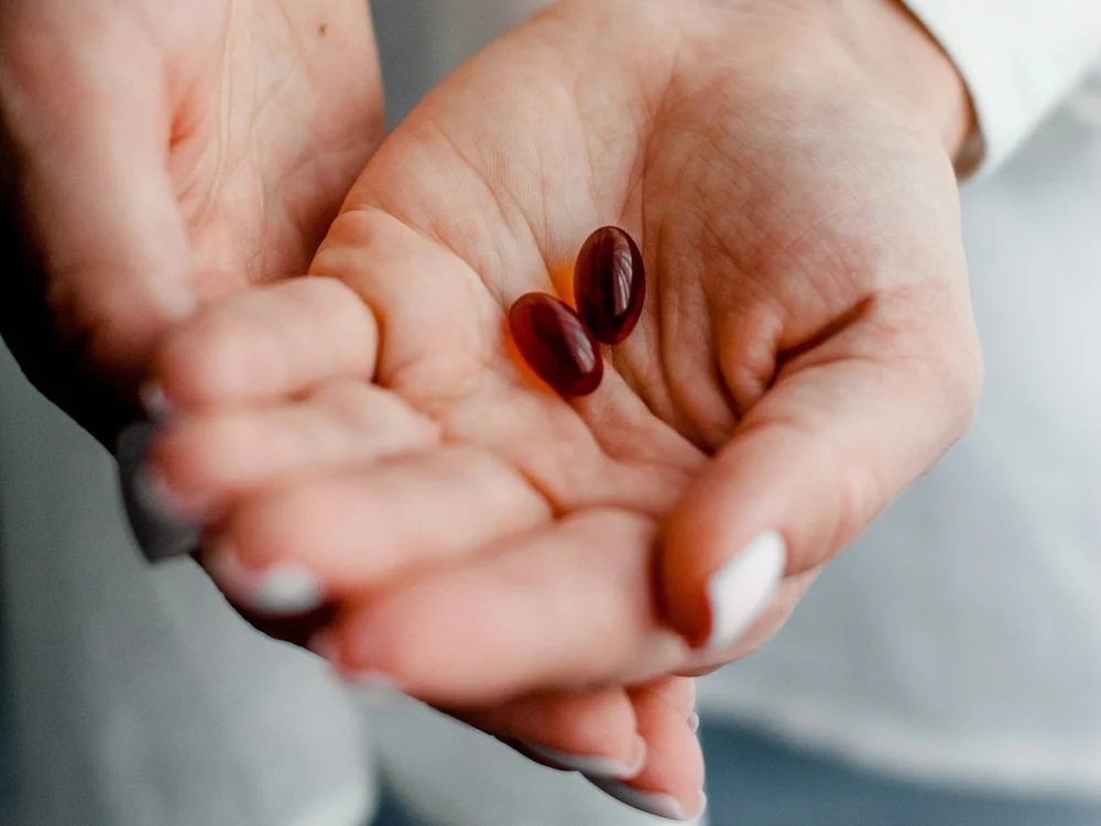 A patient holding two prescription capsules in an open hand