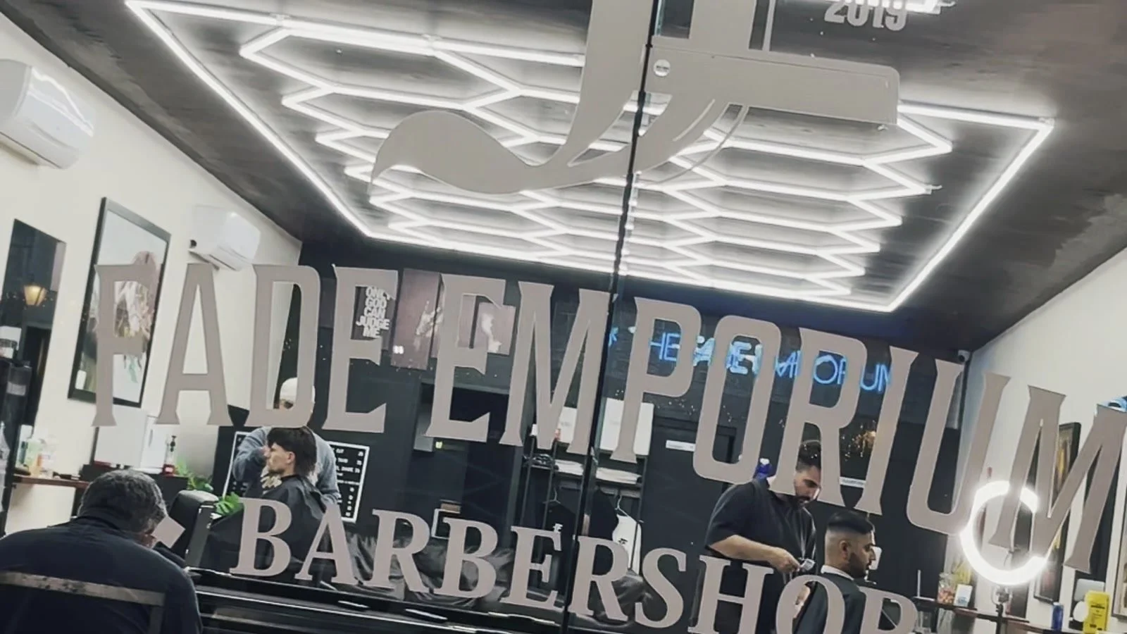 The Fade Emporium's monogram and mirrored signage above the barber stations