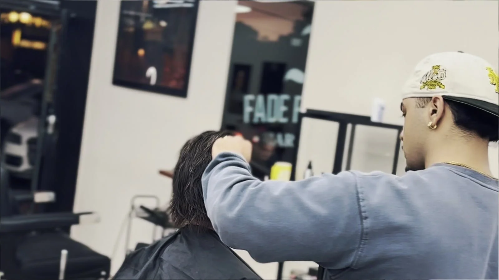 Barber lining up a client's hair with clippers at The Fade Emporium