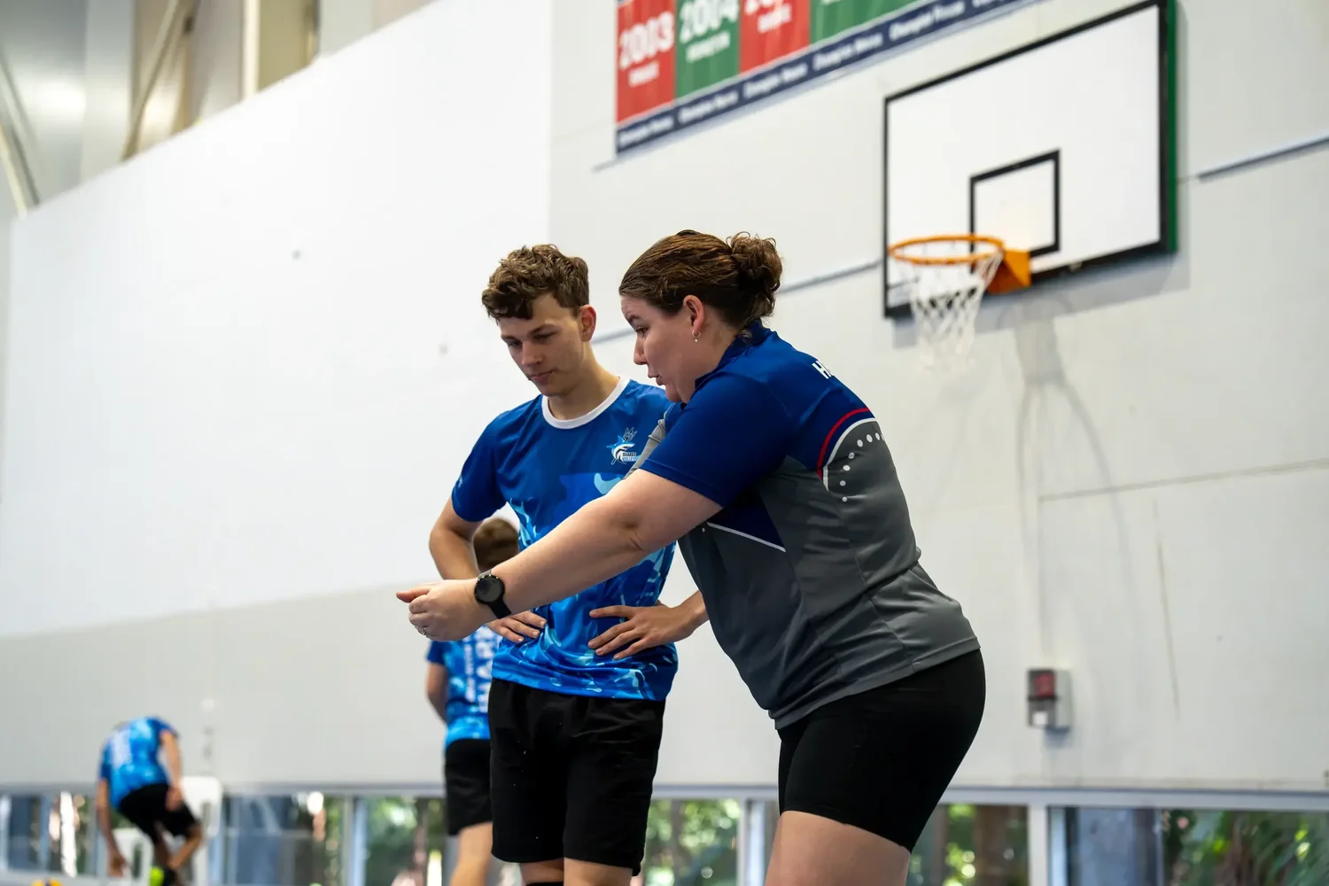 A Sharks coach in the current coaching polo demonstrating technique to an athlete