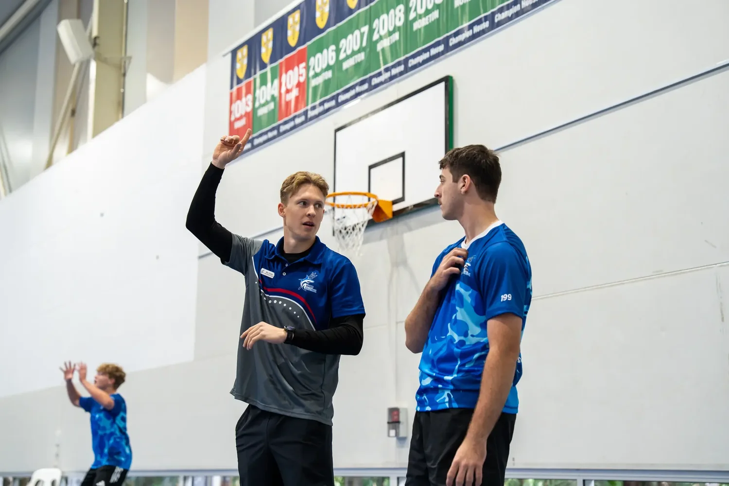 A Sharks coach in the current coaching polo giving individual feedback to an athlete
