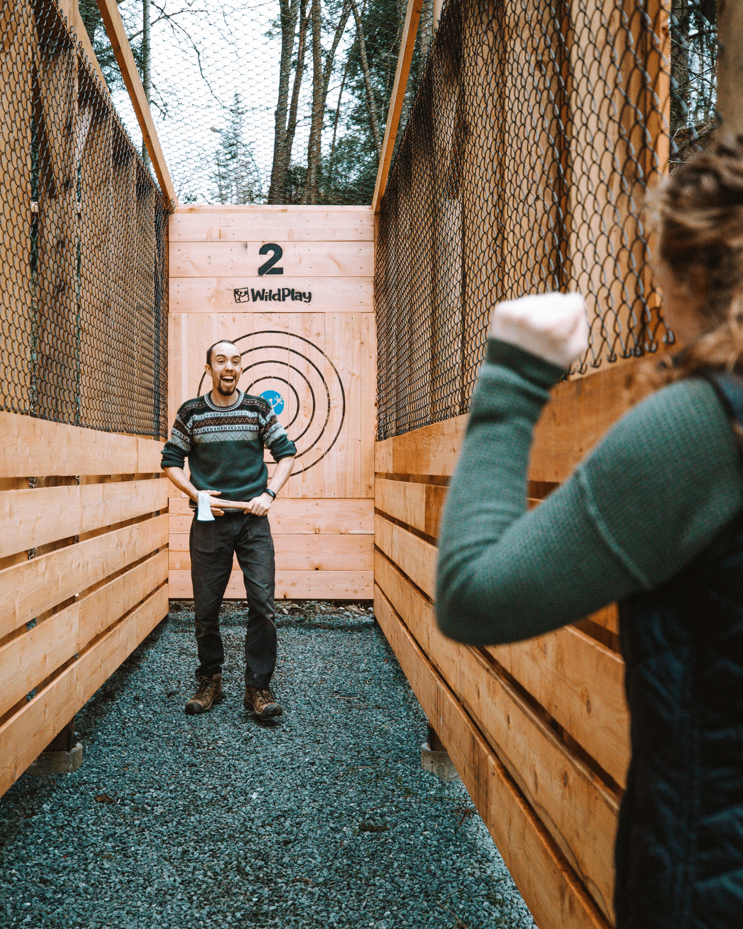 A WildPlay guide coaching a guest in the axe throwing alley