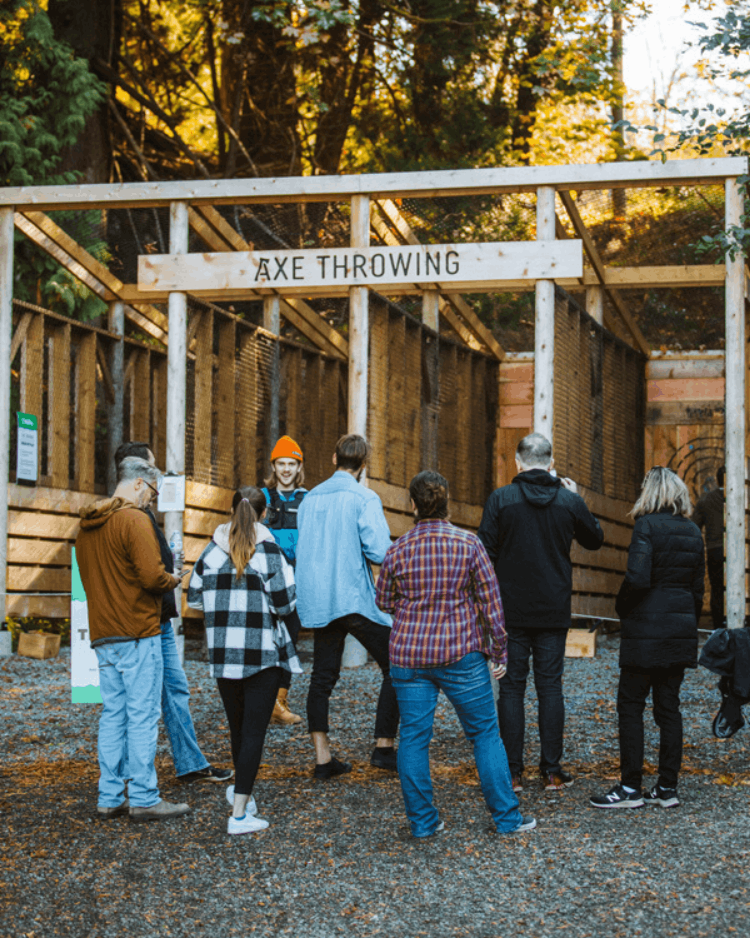 A group waiting their turn at the WildPlay axe throwing alleys, surrounded by forest
