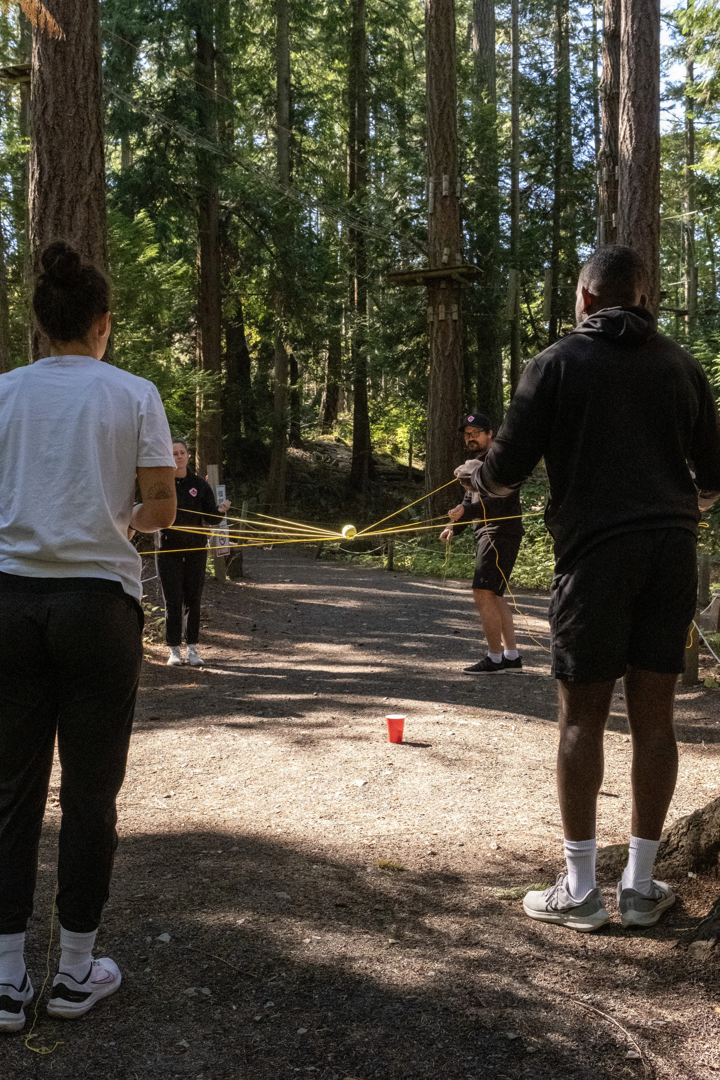 A facilitator leading a team through a ground-based string-and-ball challenge