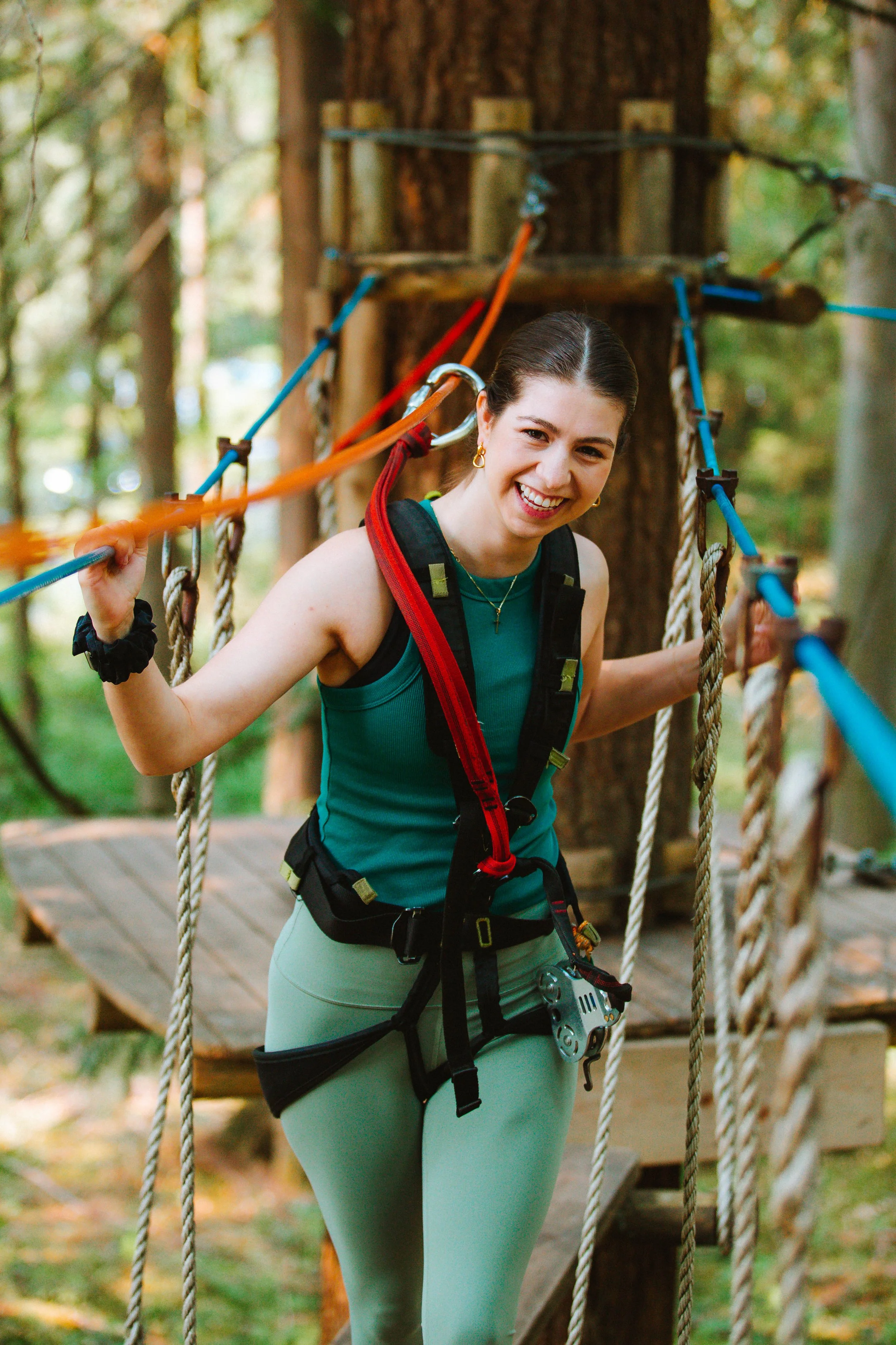 A guest harnessed up and smiling on a WildPlay Adventure Course