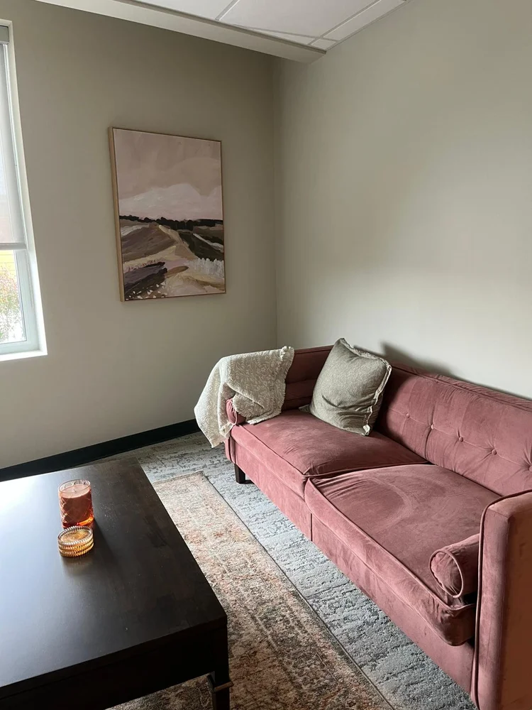 A counselling room at Summit Windermere with a green leather sofa, accent chair, and landscape artwork