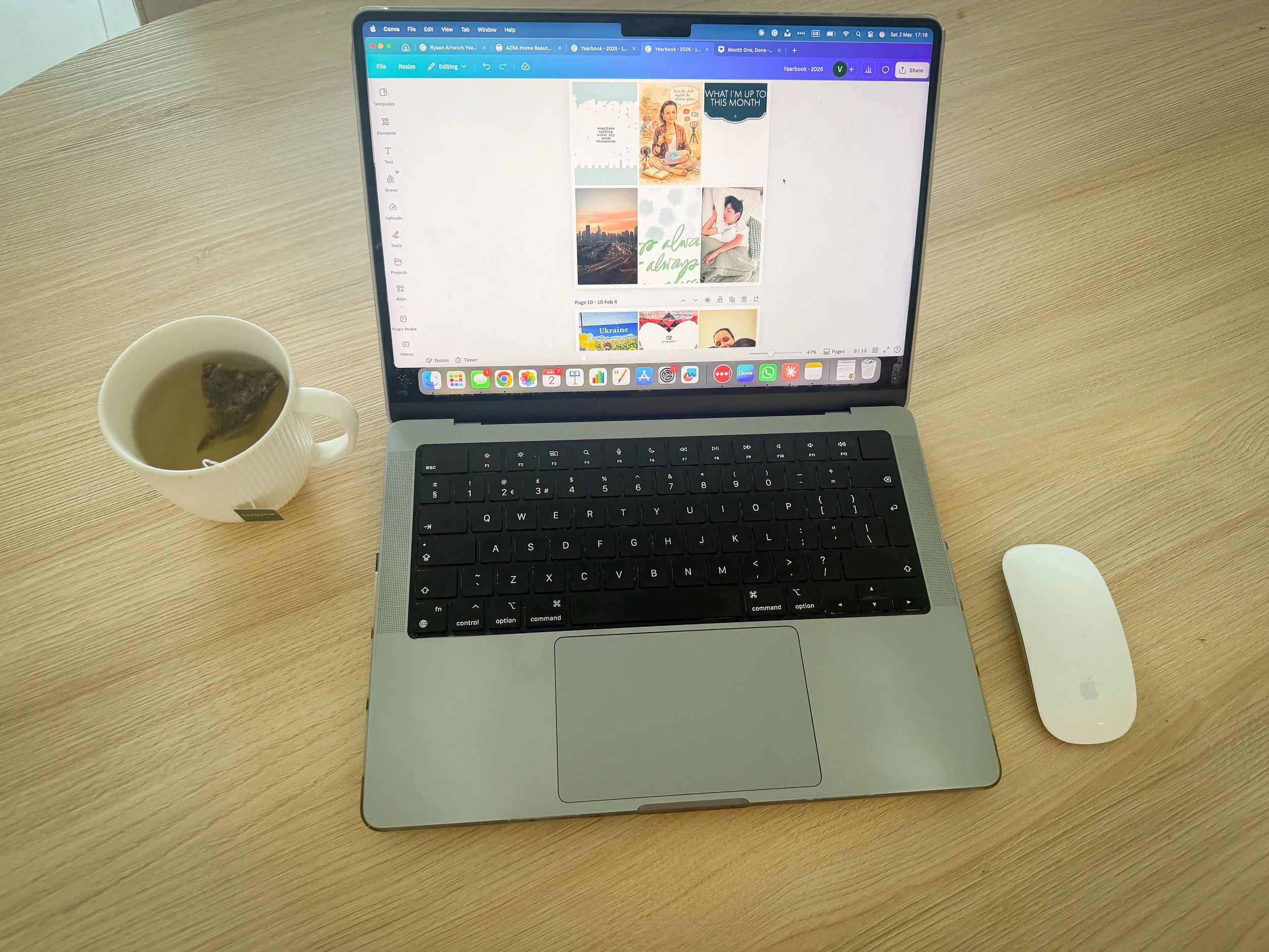 Laptop with Canva memory keeping template open alongside printed photos and a cup of tea