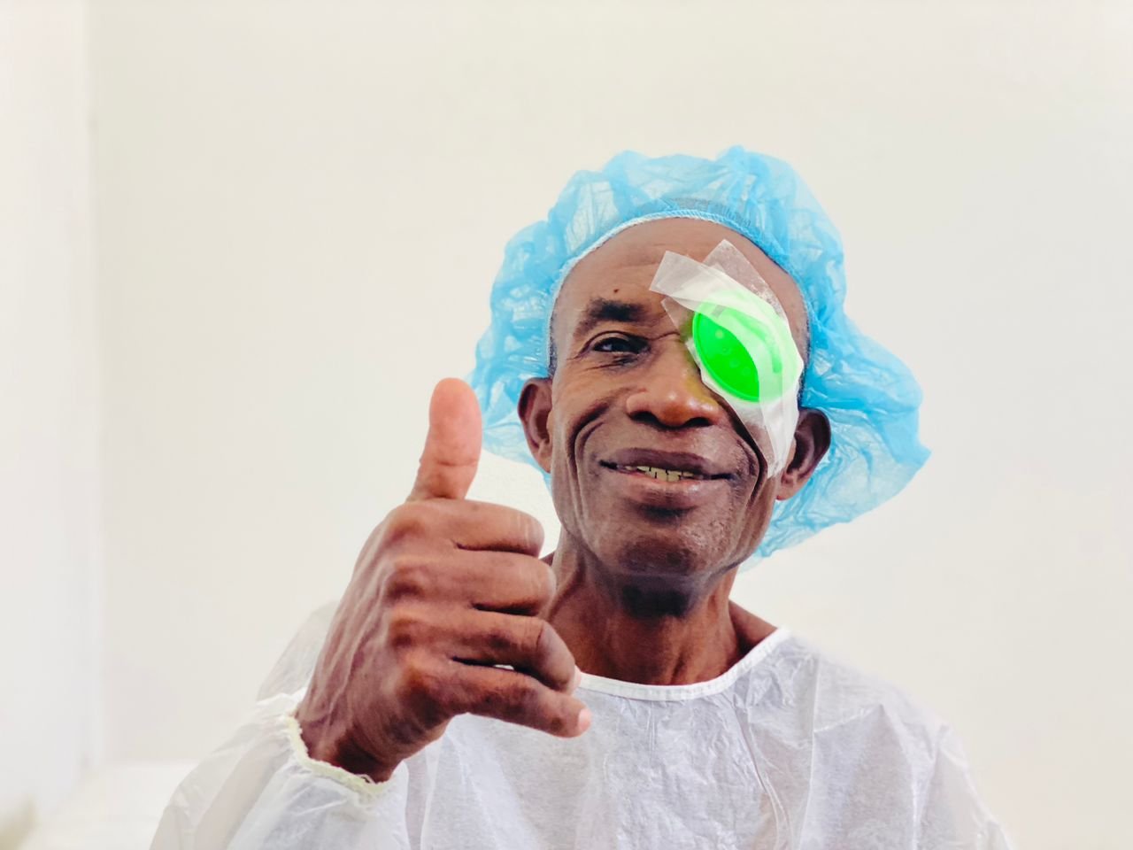A man with an eye patched after his eye surgery giving a thumb's up