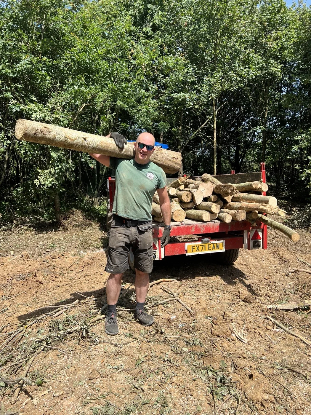 Person carrying timber beside a trailer at Nethercote Wood