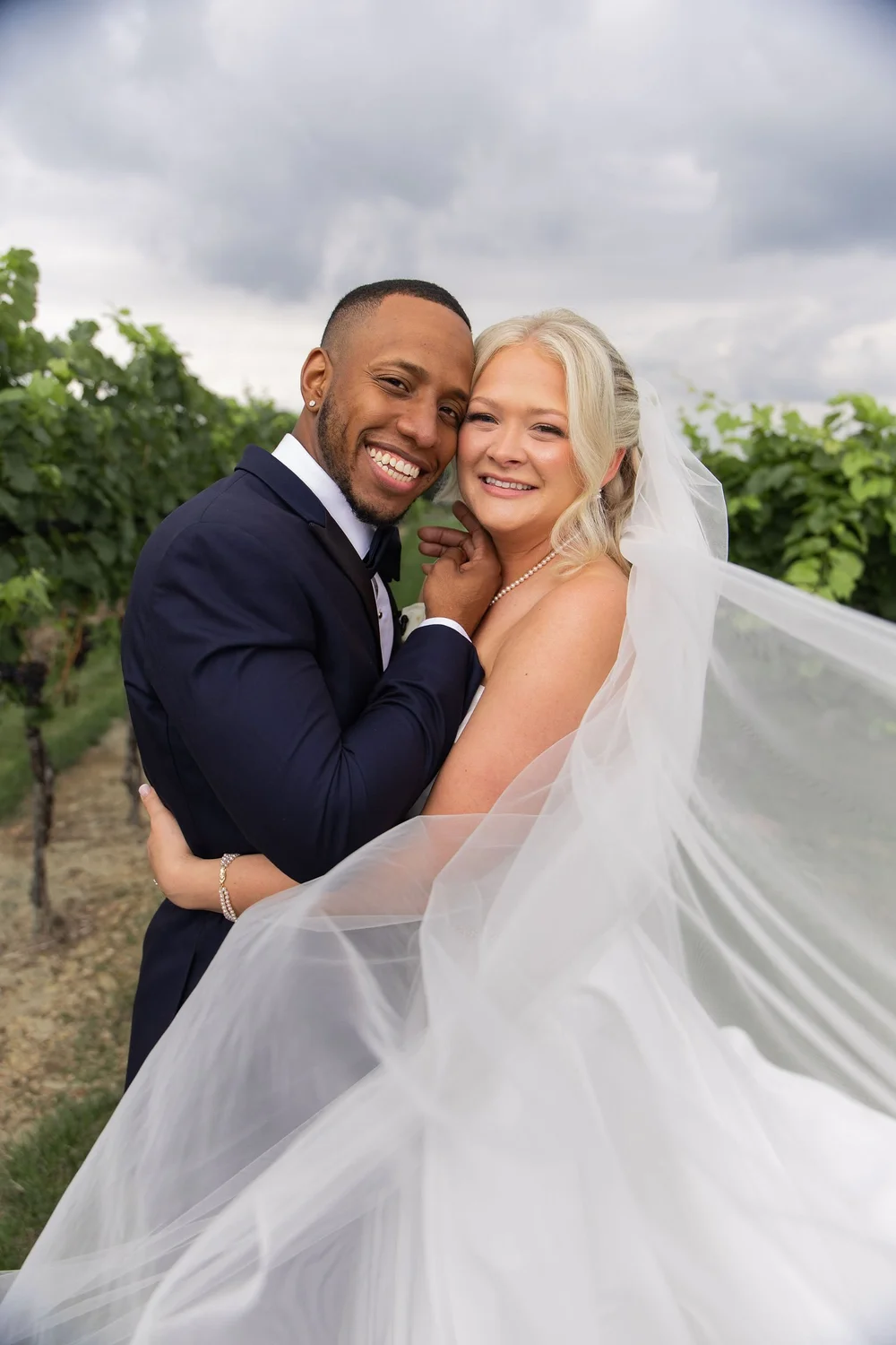 Couple embracing in the vineyard as her veil blows