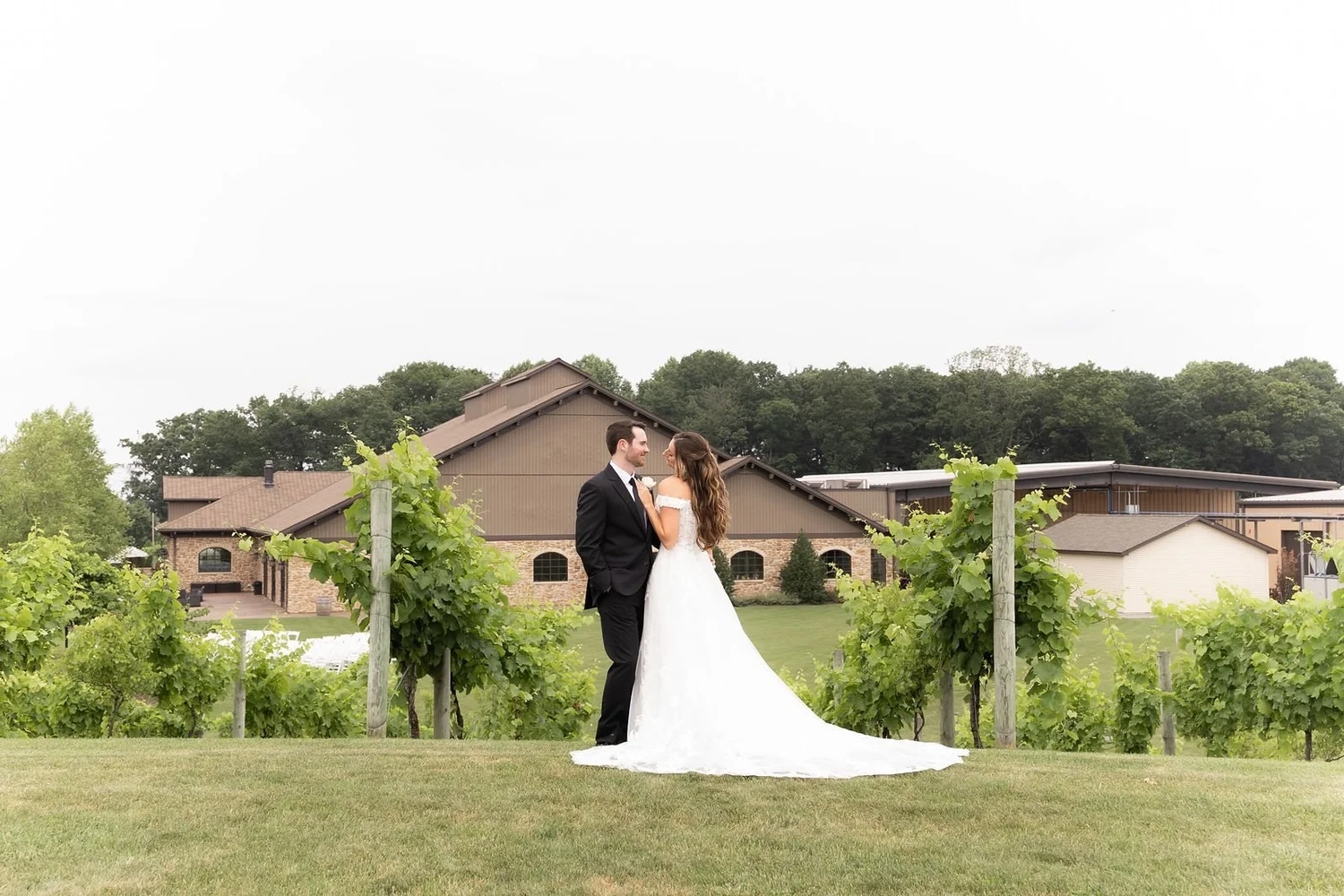 Bride and groom in the vineyard with the Folino Estate winery behind them