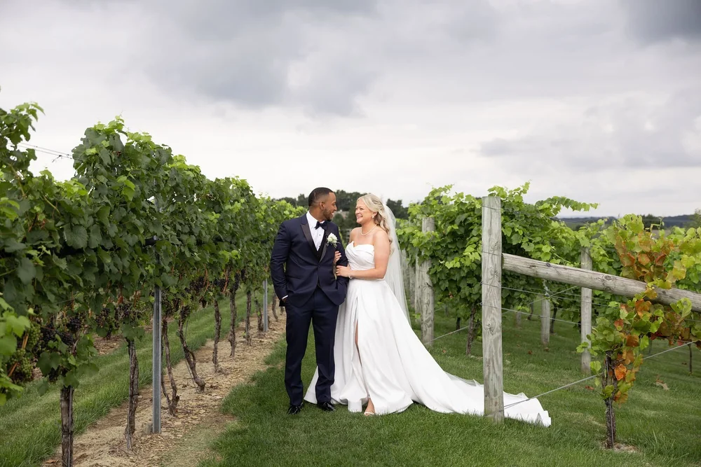 Couple standing between the vineyard rows at Folino Estate