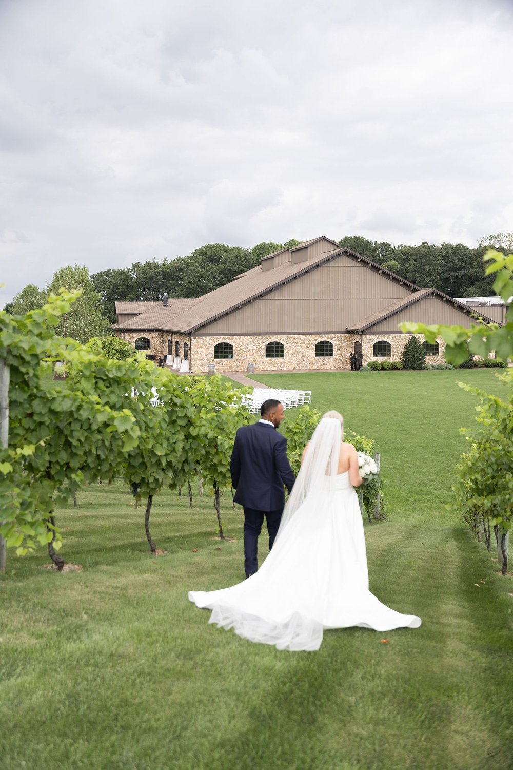 Couple in the vineyard with the winery building in the distance