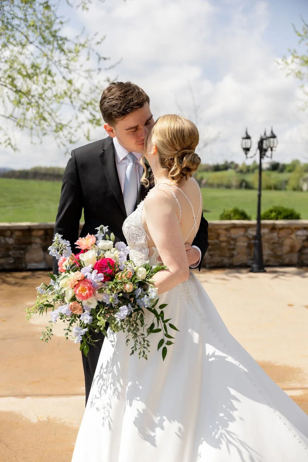 Couple kissing by the stone wall with the vineyard behind them