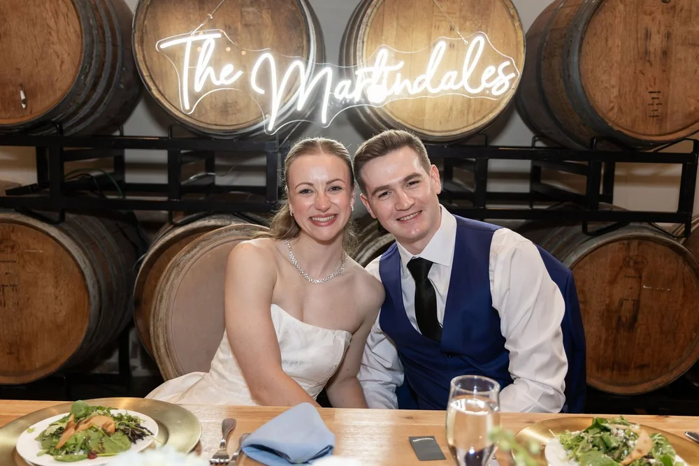 Bride and groom at their sweetheart table beneath the barrel wall
